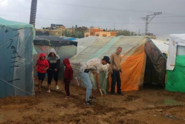 Palestinian refugees walk through the mud left by heavy rains at a UNRWA school in Deir Al Balah, central Gaza, on Thursday.