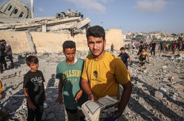 Palestinians collect the Qurans near destroyed Khalid ibn al-Walid Mosque after Israeli airstrikes