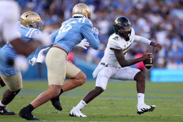 PASADENA, CALIFORNIA - OCTOBER 28: Gary Smith III #58 and Laiatu Latu #15 of the UCLA Bruins chase Shedeur Sanders #2 of the Colorado Buffaloes from the pocked during the first half of a game at Rose Bowl Stadium on October 28, 2023 in Pasadena, California. (Photo by Sean M. Haffey/Getty Images)